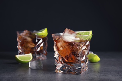 Photo of Glass of refreshing drink with ice cubes and lime on table against dark background
