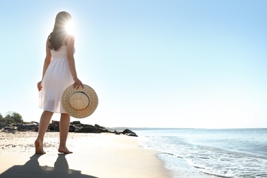 Photo of Young woman with hat walking on beach near sea. Space for text