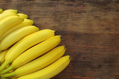 Ripe yellow bananas on wooden table, flat lay. Space for text