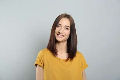 Photo of Portrait of pretty young woman with gorgeous chestnut hair and charming smile on light grey background