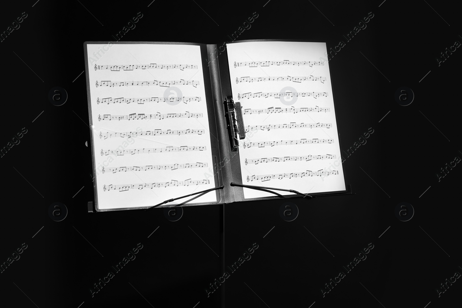 Photo of Note stand with music sheets on black background