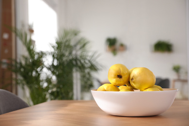 Ripe quinces on wooden table at home