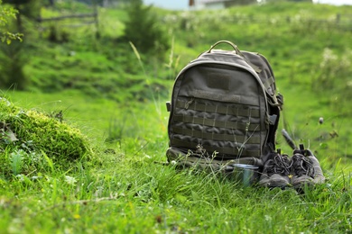 Photo of Backpack and hiking boots in green mountain valley. Summer camping