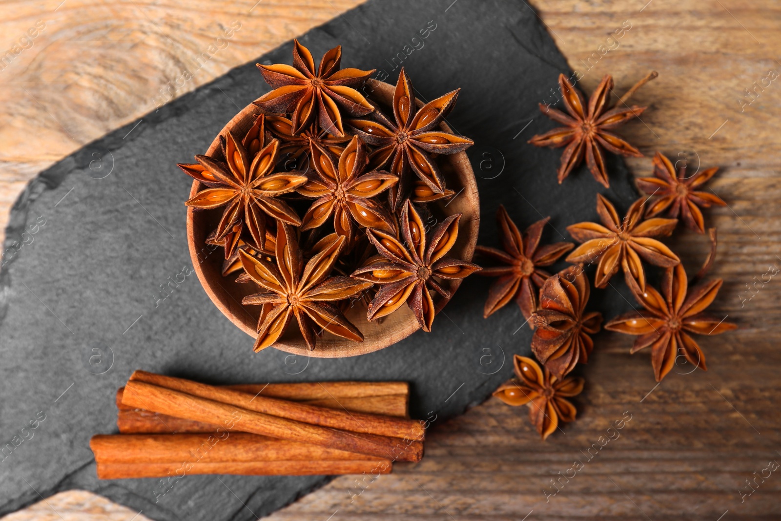 Photo of Aromatic cinnamon sticks and anise stars on wooden table, flat lay