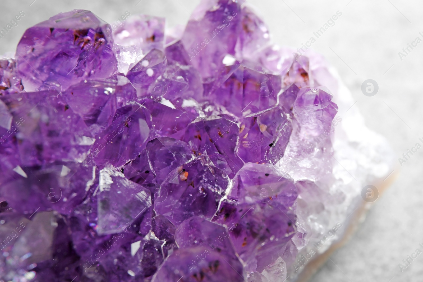 Photo of Beautiful purple amethyst gemstone on grey table, closeup