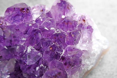 Photo of Beautiful purple amethyst gemstone on grey table, closeup