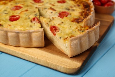 Photo of Delicious homemade cheese quiche on light blue wooden table, closeup