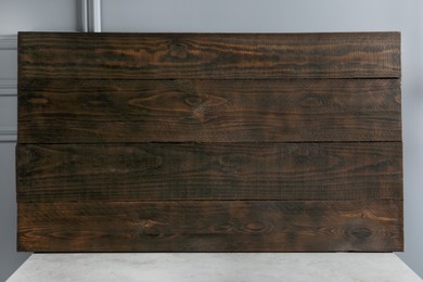 Photo of Dark wooden board on table near light grey wall