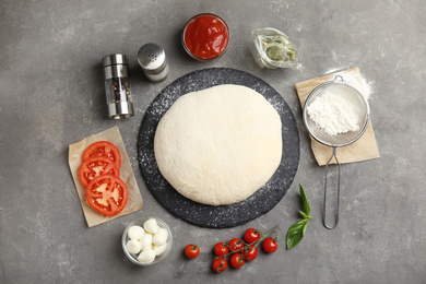 Photo of Flat lay composition with dough and fresh ingredients for pizza on grey table