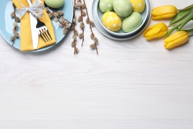 Photo of Festive Easter table setting with eggs on white wooden background, flat lay. Space for text