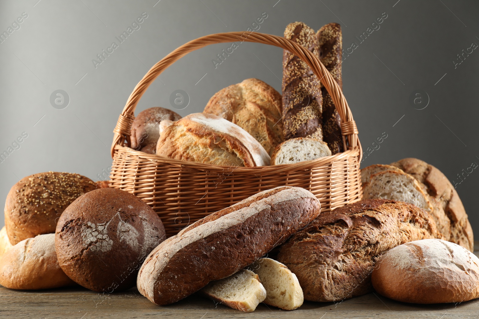 Photo of Wicker basket with different types of fresh bread on wooden table