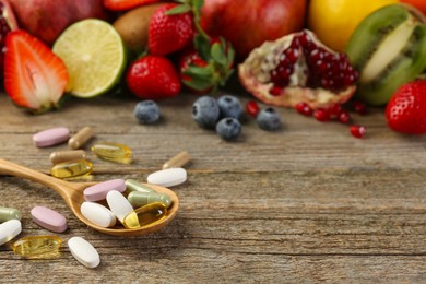 Photo of Different vitamin pills and fresh fruits on wooden table. Space for text