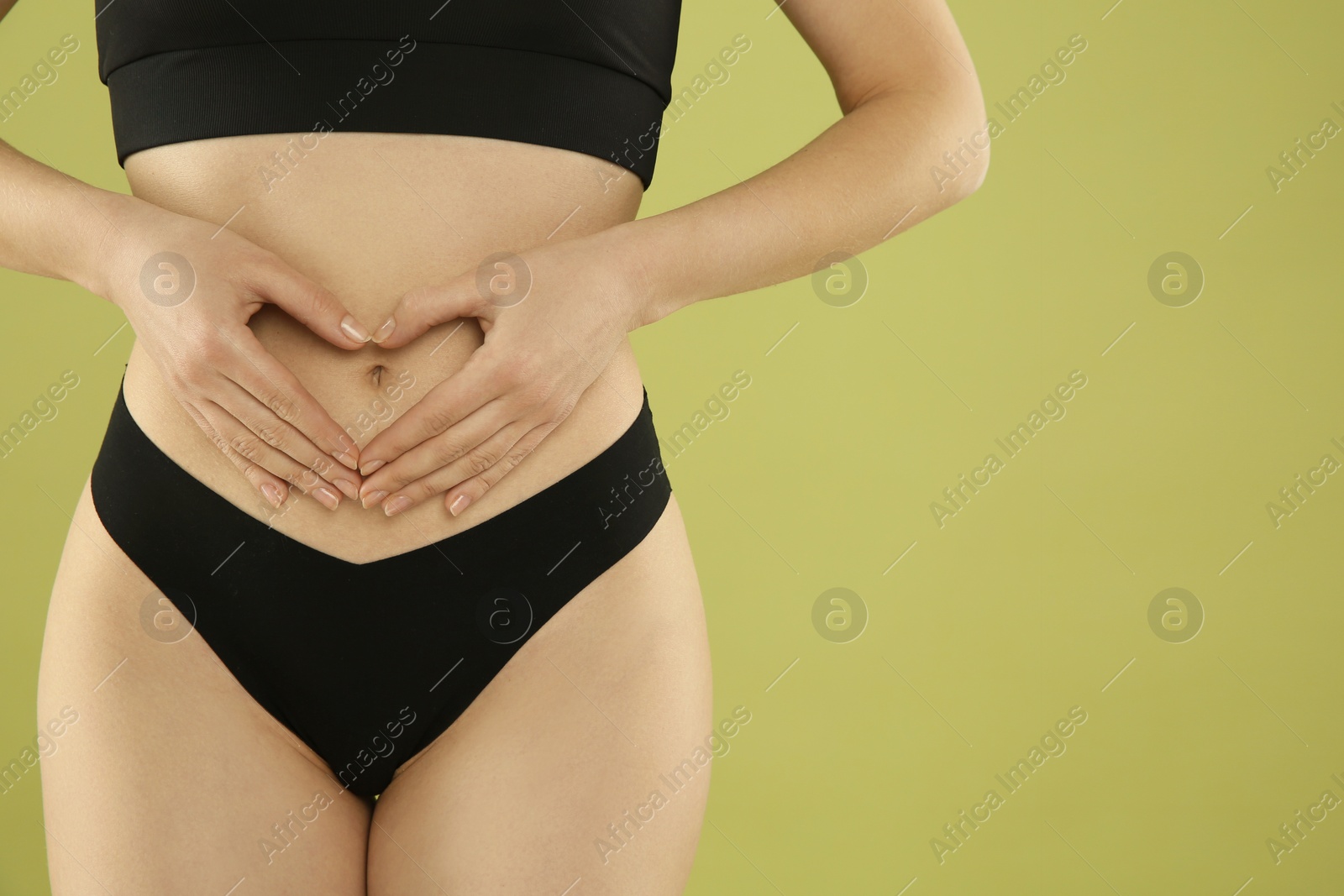 Photo of Gynecology. Woman in underwear making heart with her hands on green background, closeup. Space for text