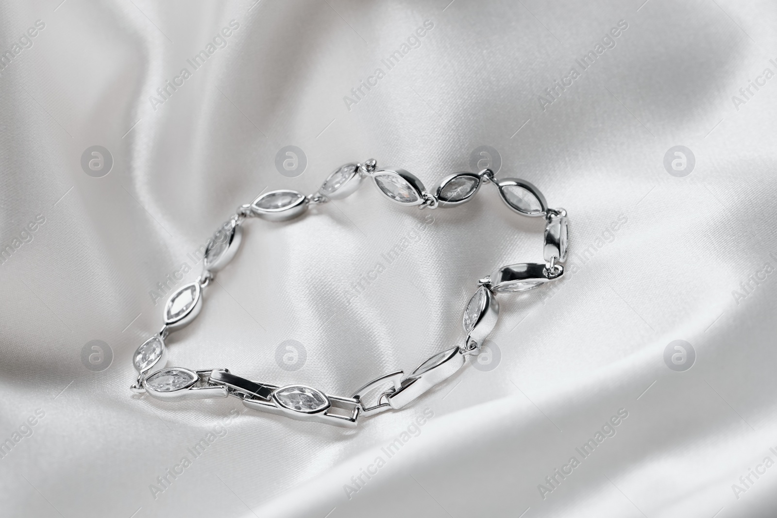 Photo of Beautiful bracelet with gemstones on white fabric. Luxury jewelry