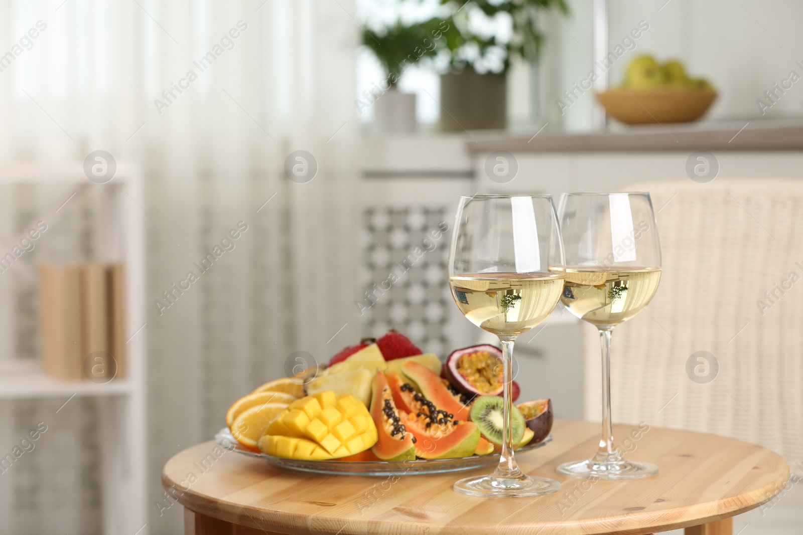 Photo of Delicious exotic fruits and glasses of wine on wooden table indoors