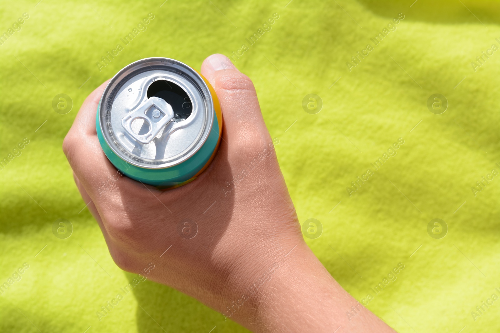 Photo of Woman holding aluminum can with beverage on yellow blanket, top view. Space for text