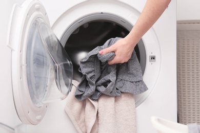 Photo of Housewife putting clothes into washing machine