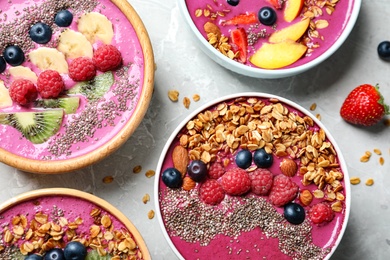 Photo of Acai smoothie bowls with granola and berries on marble table, flat lay