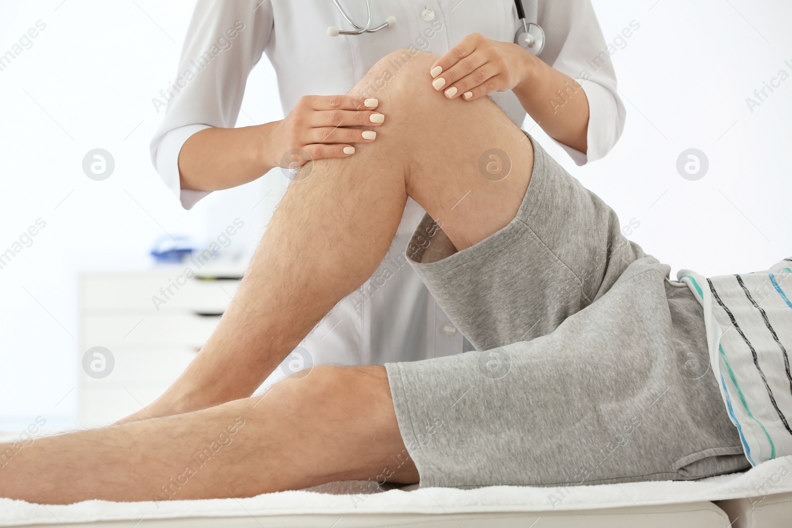 Photo of Doctor examining male patient with injured leg, closeup