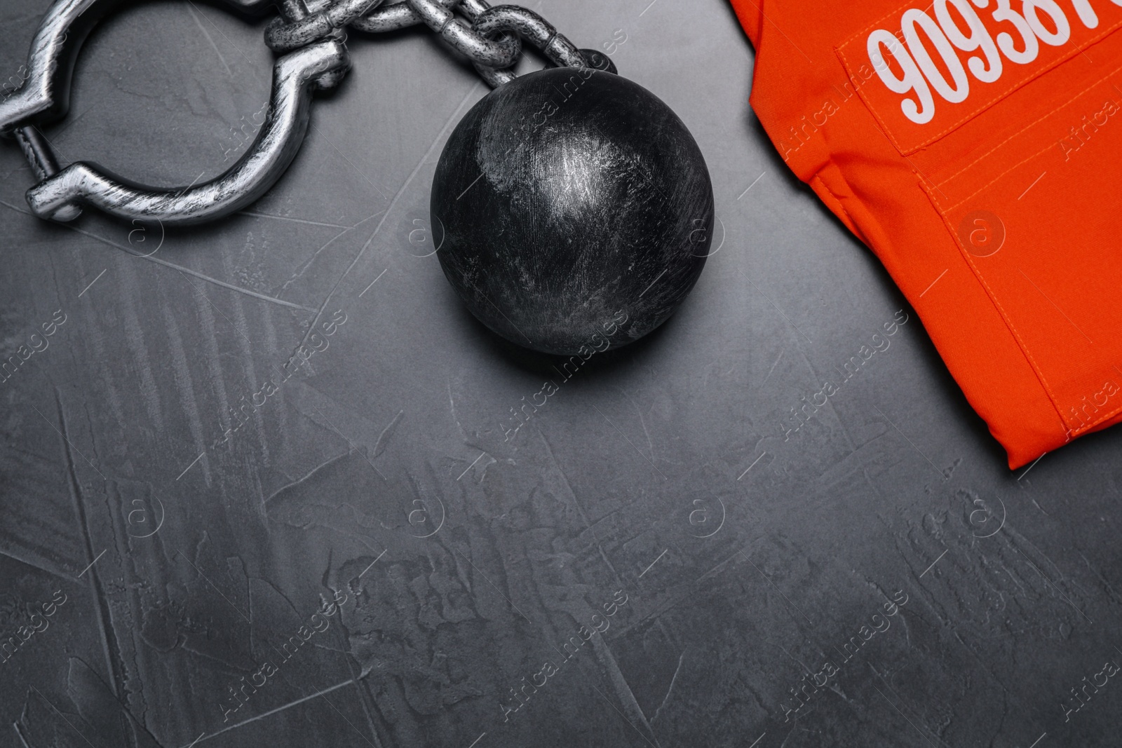 Photo of Prisoner ball with chain and jail clothes on grey table, flat lay. Space for text