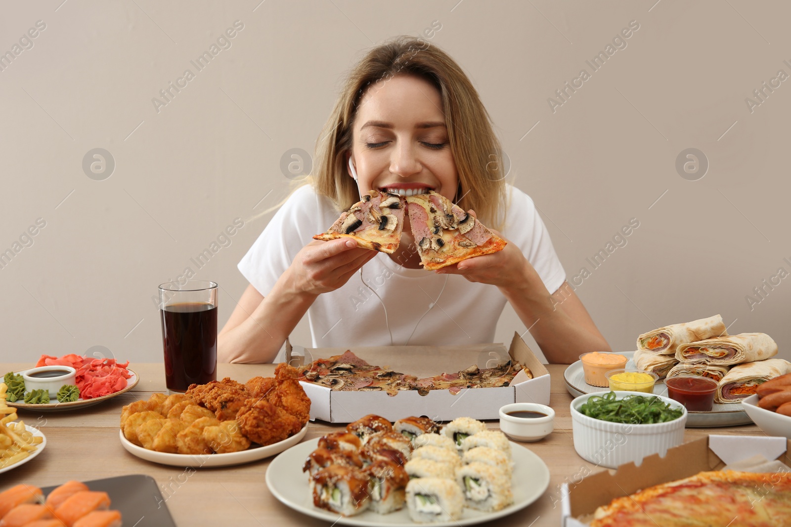 Photo of Food blogger eating at table against beige background. Mukbang vlog