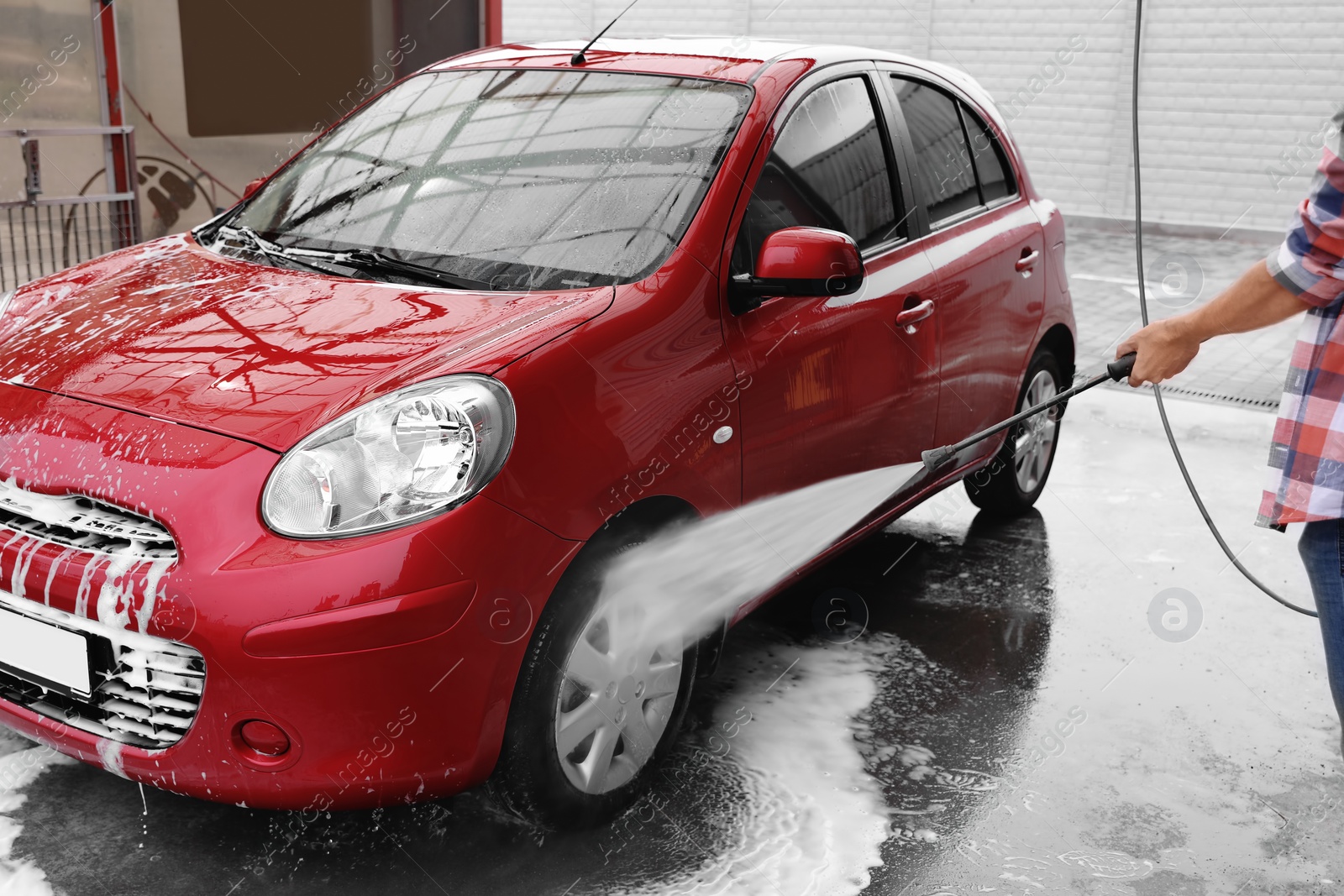 Photo of Man cleaning auto with high pressure water jet at car wash