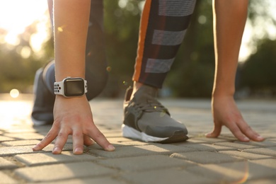 Photo of Woman wearing modern smart watch during training outdoors, closeup