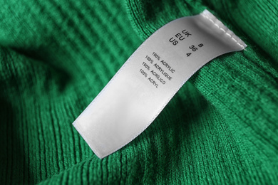 Photo of Clothing label with material content on green shirt, closeup view