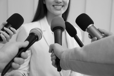 Image of Businesswoman giving interview to journalists indoors, closeup. Black and white effect