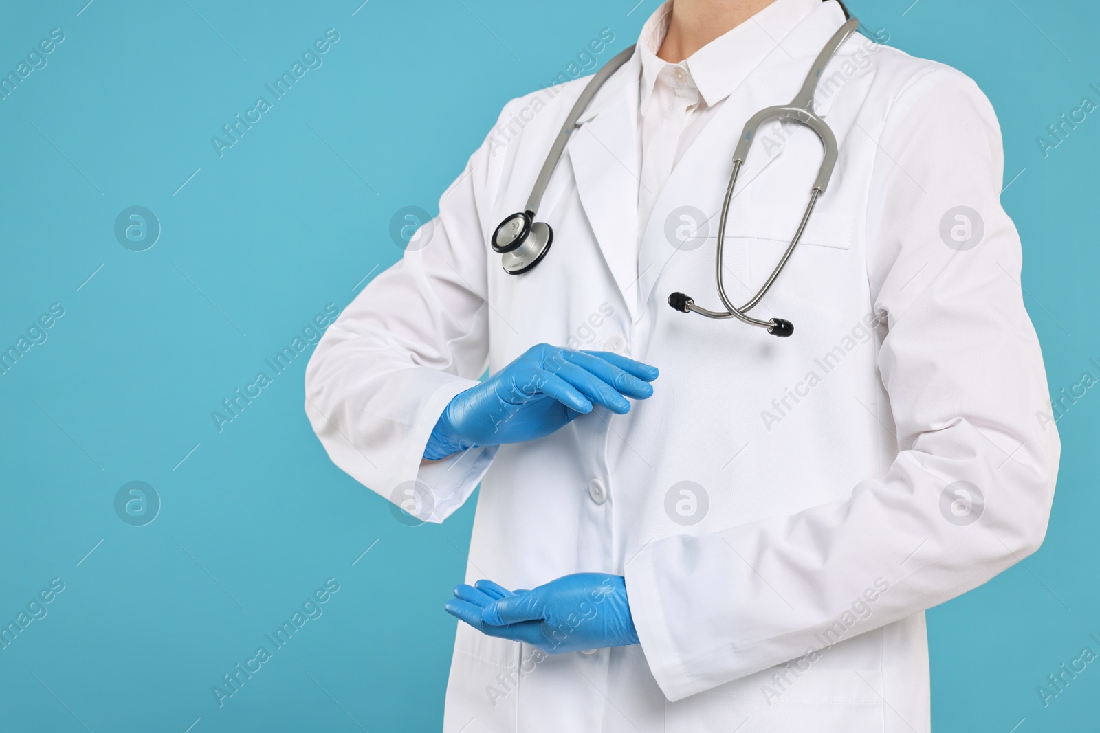 Photo of Doctor with stethoscope holding something on light blue background, closeup. Space for text