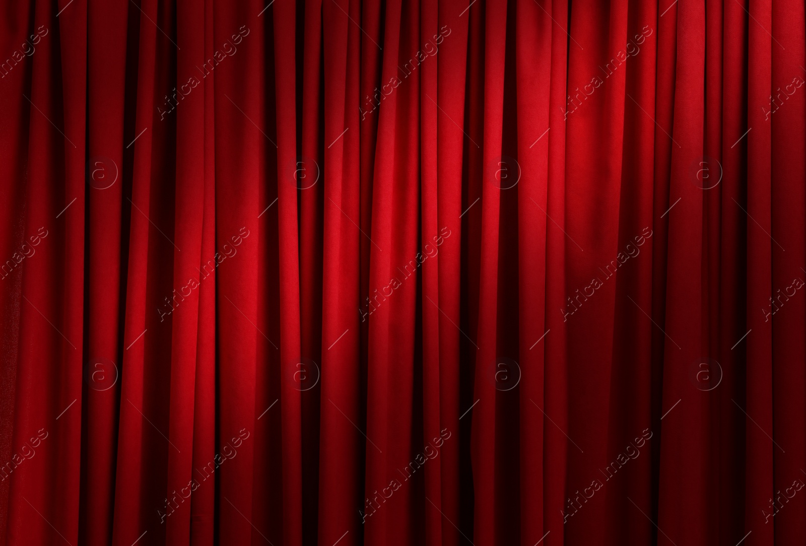 Image of Spotlight illuminating closed red stage curtains. Start of performance 