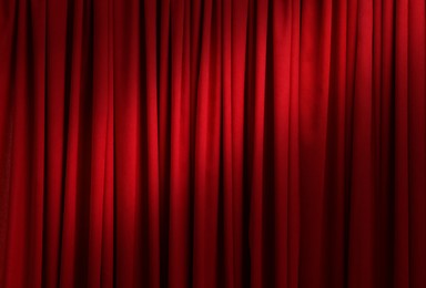 Spotlight illuminating closed red stage curtains. Start of performance 