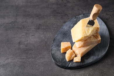 Photo of Parmesan cheese with board and knife on grey table. Space for text