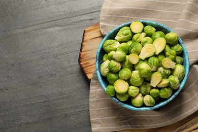 Photo of Bowl with fresh Brussels sprouts on grey table, top view. Space for text