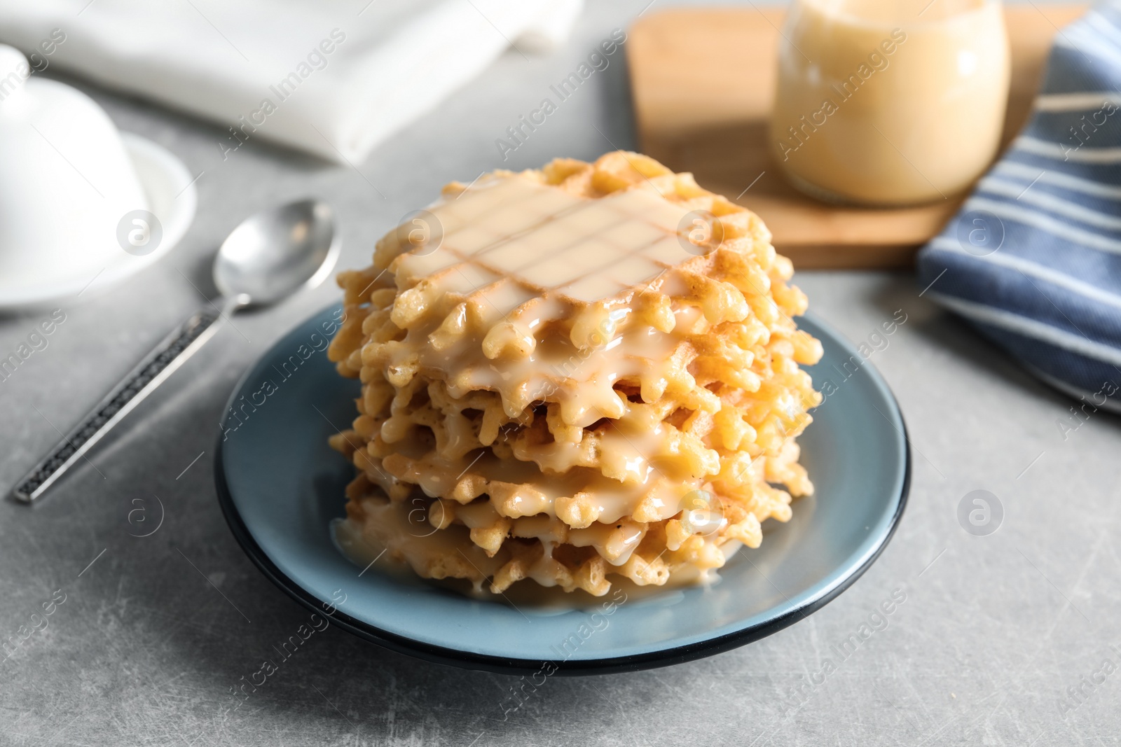 Photo of Plate with waffles and condensed milk on grey table. Dairy product