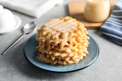 Photo of Plate with waffles and condensed milk on grey table. Dairy product