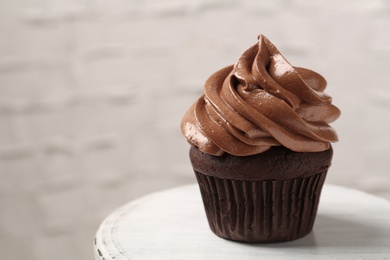 Photo of Delicious chocolate cupcake with cream on white table, closeup. Space for text