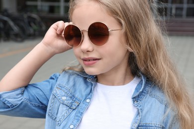 Photo of Girl wearing stylish sunglasses on street near building