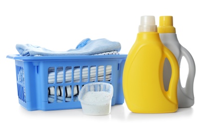 Photo of Basket with fresh baby laundry, washing powder and bottles of detergent on white background