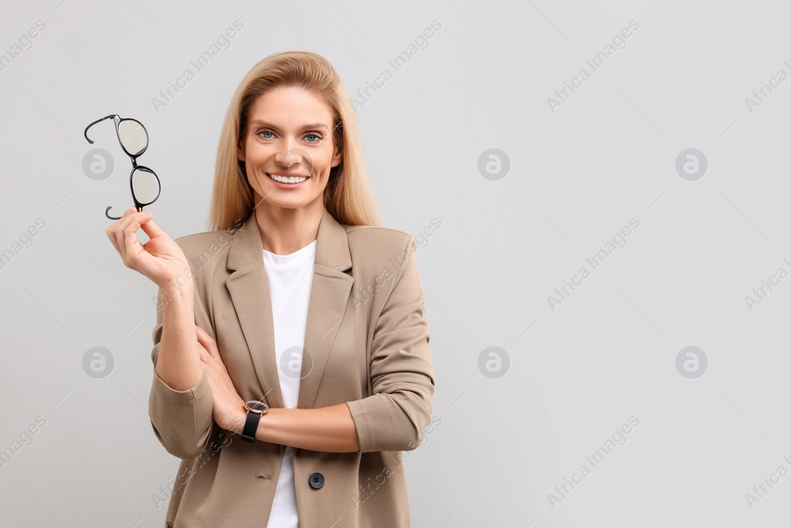 Photo of Portrait of smiling middle aged businesswoman with glasses on light grey background. Space for text