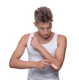 Photo of Handsome man putting sticking plaster onto elbow on white background