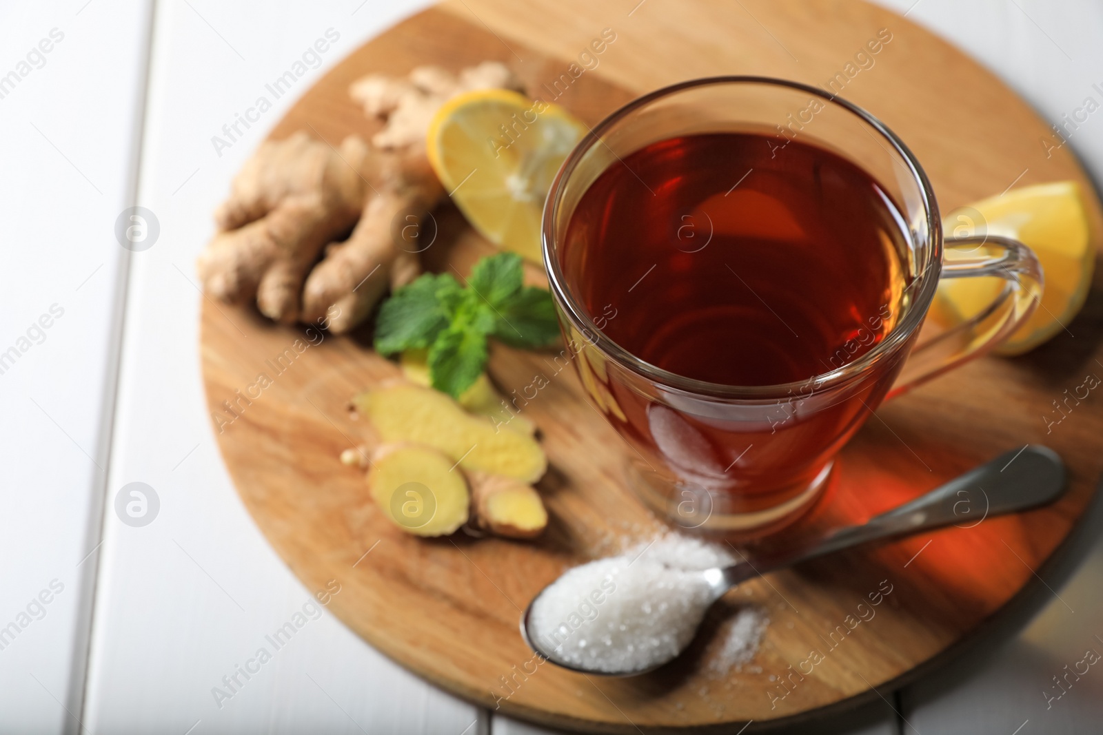 Photo of Cup of delicious ginger tea and ingredients on white wooden table, above view. Space for text