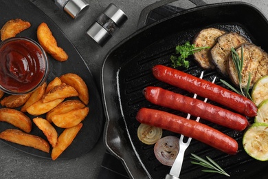 Delicious grilled sausages and vegetables on grey table, flat lay