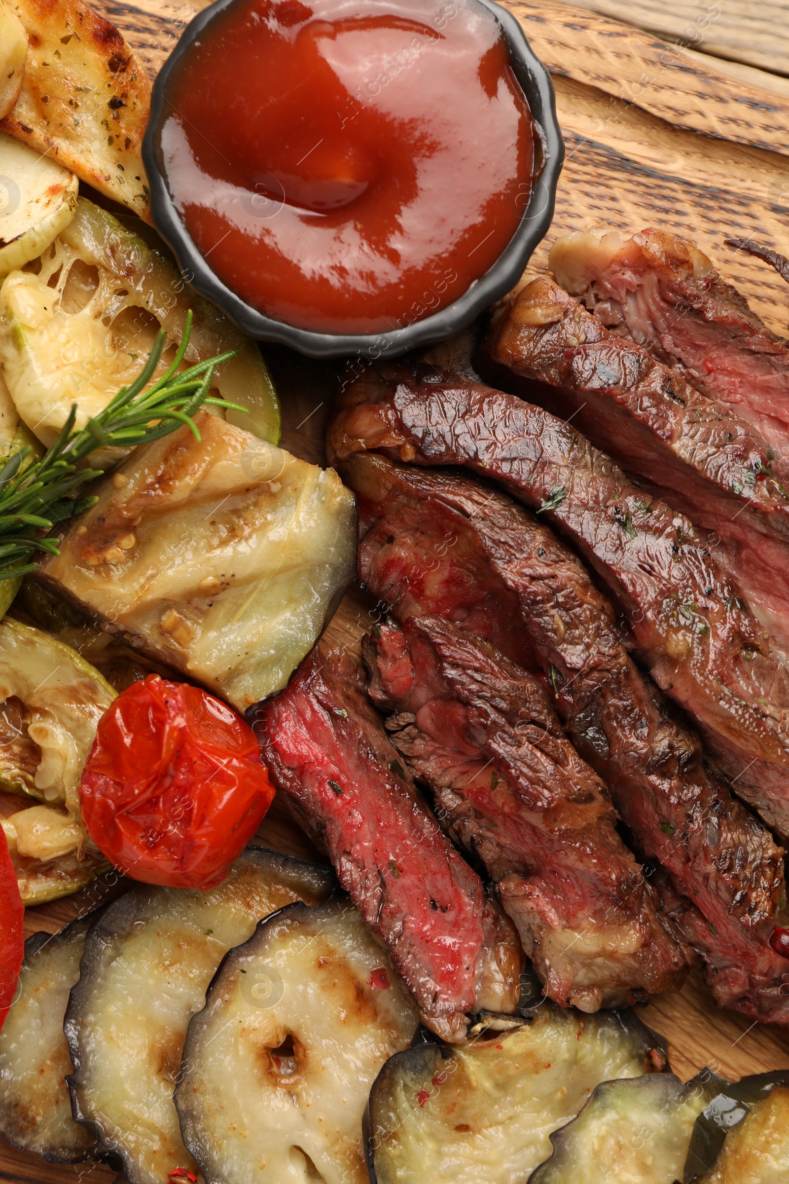 Photo of Delicious grilled beef with vegetables, rosemary and tomato sauce on table, top view