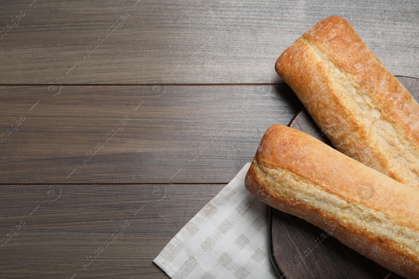 Photo of Tasty baguettes on wooden table, top view. Space for text