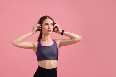 Photo of Woman in sportswear and headphones on pink background, space for text