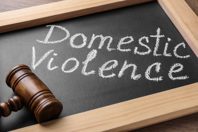 Photo of Blackboard with words DOMESTIC VIOLENCE and gavel on table