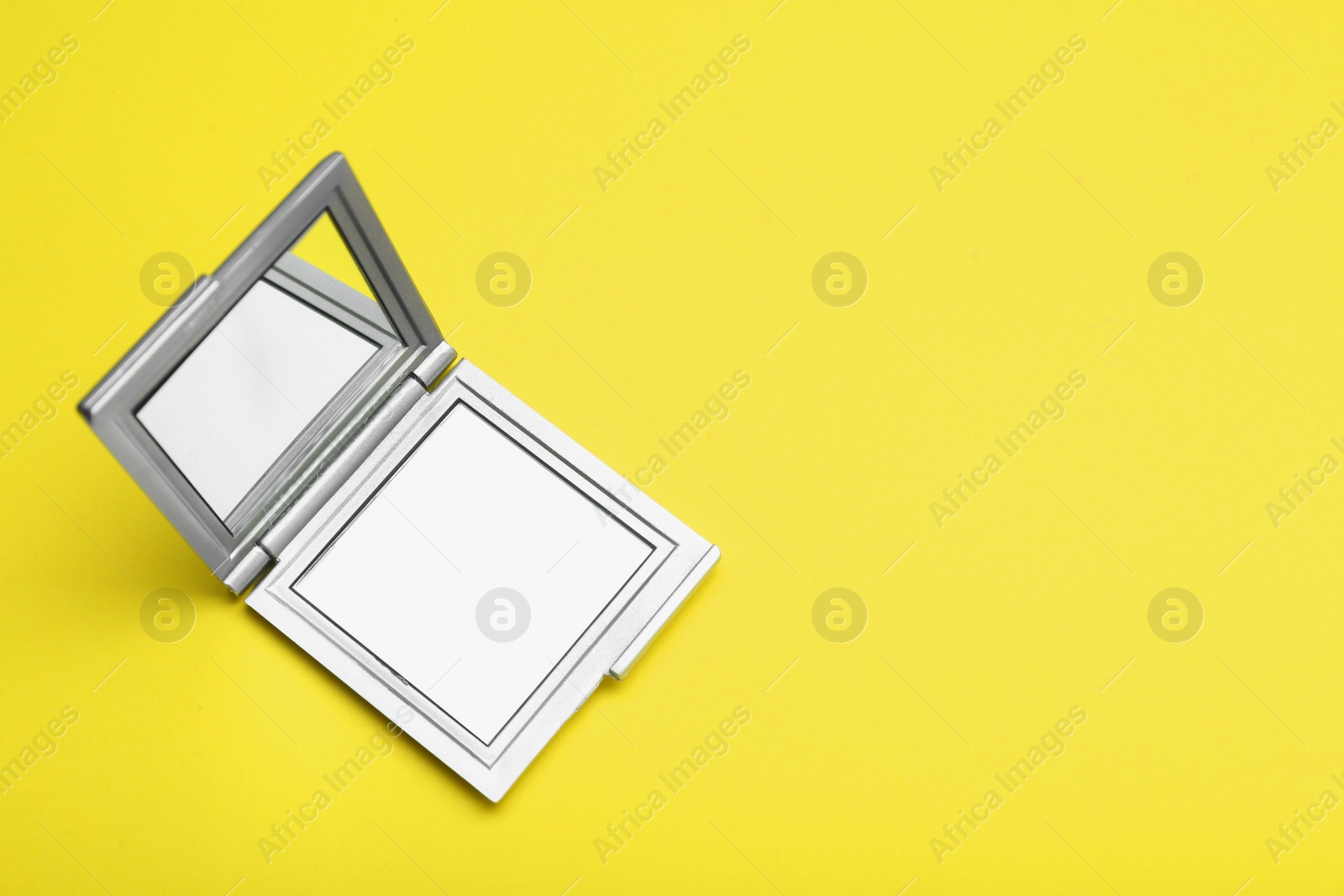 Photo of Stylish cosmetic pocket mirror on yellow background, top view. Space for text