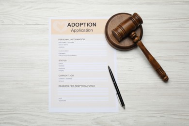 Adoption application, gavel and pen on white wooden table, flat lay
