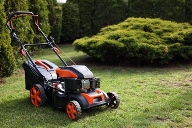 Modern lawn mower on green grass in garden